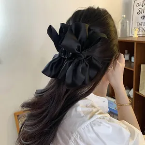 Vista dettagliata della clip per capelli oversize in raso nero con fiocco elegante e chic