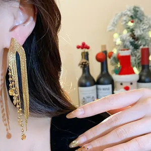 Close-up of 18k gold plated long tassel earrings with bead accents in a festive setting
