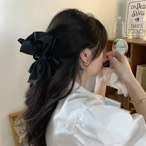 Elegante molletta per capelli con grande fiocco in raso nero indossata dal modello