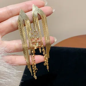 Close-up of elegant 18k gold-plated fringe earrings with bead chains and tiny heart charms.