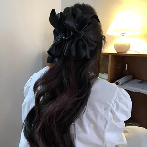 Vista posteriore di una grande clip per capelli in raso nero su lunghi capelli mossi