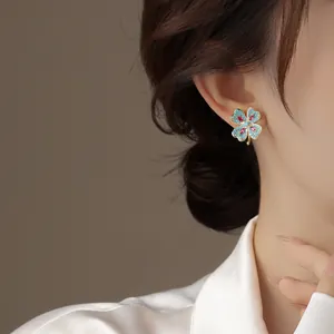 Close-up of a vintage four-leaf clover earring with blue and pink stones on model.