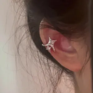 Macro view of a sparkling zircon star ear cuff elegantly worn on a human ear bone.