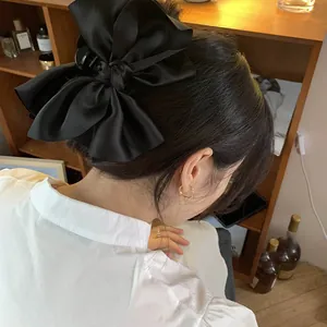 Dettaglio di un elegante fermaglio per capelli con fiocco in raso nero su capelli scuri