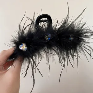 Detail view of black feather hair claw clip with sparkling heart-shaped rhinestone accents.