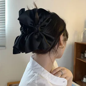 Grande molletta per capelli con fiocco in raso nero su modella, dettaglio elegante