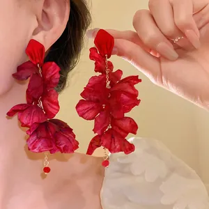 Macro view of red fabric flower tassel earrings showing delicate petal texture.