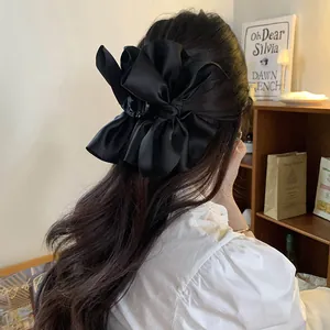 Elegante vista posteriore di una grande molletta a fiocco in raso nero su capelli lunghi mossi