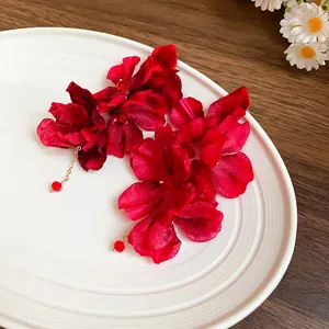 Detailed shot of vibrant red fabric flower tassel earrings on a white decorative plate