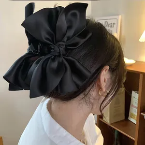 Primo piano di una grande pinza per capelli in raso nero con fiocco
