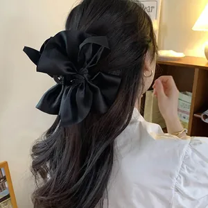 Vista posteriore di un elegante fermaglio per capelli in raso nero a forma di fiocco