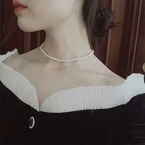 Detailed macro view of a French baroque small pearl choker necklace worn on a female neck