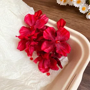 Close-up detail of vibrant red fabric flower tassel earrings with silver needle studs