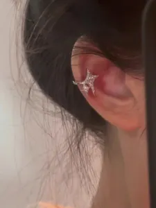 Elegant silver zircon star ear cuff shown worn on the ear bone, no piercing required.