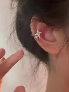 Close-up detail showing a sparkling Korean style zircon star ear cuff worn on the ear bone