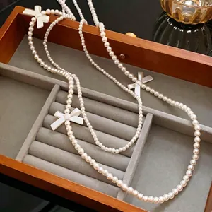 Élégant collier de perles multicouches avec nœuds blancs dans une boîte à bijoux