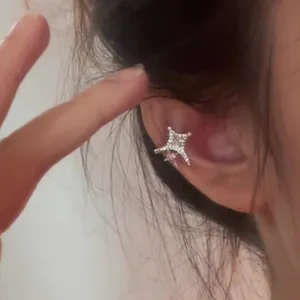 Sparkling zircon star ear cuff shown worn on the helix of a woman's ear for detail view
