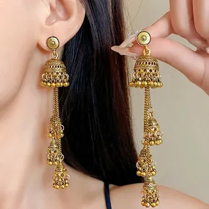 Orecchini jhumka pendenti stile palazzo vintage dorati indossati da una modella da vicino