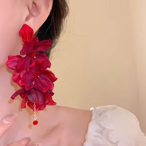 Detailed view of deep red fabric flower tassel earrings with delicate beading
