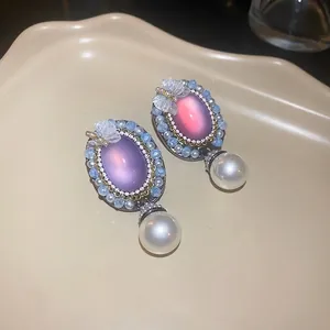 Vintage oval earrings with butterfly detail, beads, and pearl drops on a cream tray