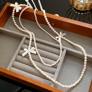 Détail élégant d'un collier de perles superposées avec nœuds blancs en boîte à bijoux