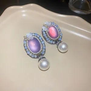 Detailed view of vintage palace style oval earrings with butterfly and pearl drops.