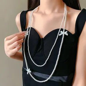 Vue détaillée d'un collier de perles artificielles avec nœuds blancs élégants.