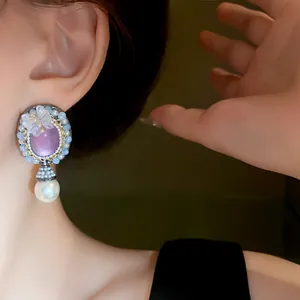 Close-up view of vintage palace style earrings featuring purple stone and pearl drop