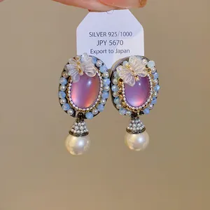 Close-up detail of elegant vintage purple stone earrings with pearl and butterfly accents