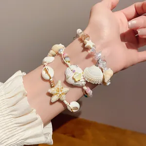 Detailed close-up showing layered handmade seashell and starfish bracelets on a wrist