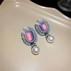 Close-up of vintage court style oval earrings with purple stone and hanging pearl