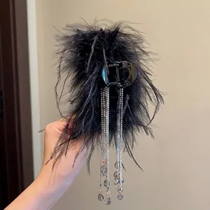 Close-up of elegant black feather hair claw clip with sparkling rhinestone tassels