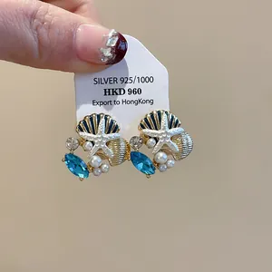 Detailansicht von Seestern- und Muschelohrringen mit Perlen und blauen Kristallen Schmuck.