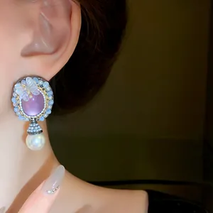 Close-up of retro silver needle earring with purple gem, butterfly, and pearl.