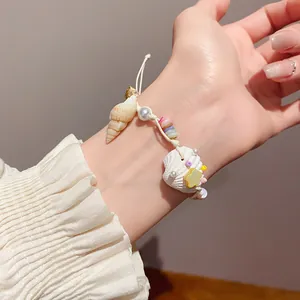 Close-up of bohemian seashell bracelet with pearl and starfish charms on wrist