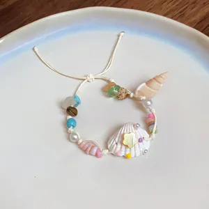 Handmade shell and natural stone beach bracelet with pearl accents on a ceramic plate