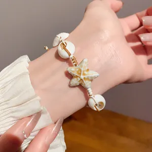 Detail shot of a handmade woven bracelet with ceramic starfish and natural shells
