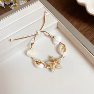 Handmade woven bracelet featuring ceramic starfish and natural shells for a beach look.