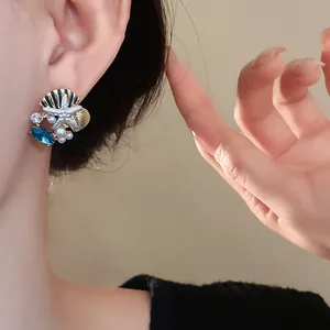 Detailansicht von Seestern- und Muschelohrringen mit Perlen und blauem Edelstein-Design