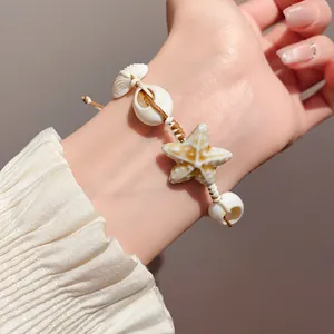 Detail of handmade beach bracelet with starfish and seashell charms on wrist