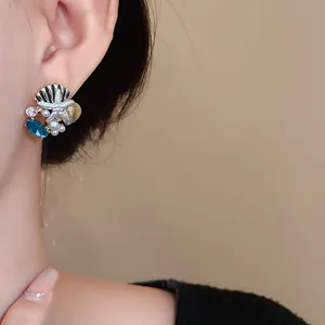 Detailaufnahme von Ohrringen mit Seestern, Muschel, Perle und blauem Kristall