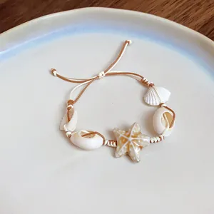 Macro view of handmade woven bracelet with cowrie shells and ceramic starfish detail