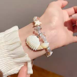 Detail of natural stone and pearl bracelet with seashell charms on model's wrist