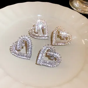 Eleganti orecchini a cuore in zircone con ago d'argento su un piatto di ceramica.