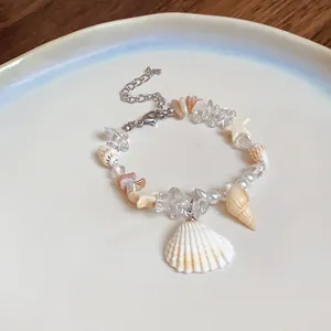 Detailed shot of a beach-style bracelet with natural stones, pearls, and seashells.