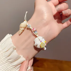 Close-up detail shot of bohemian shell pearl bracelet on wrist with soft lighting.