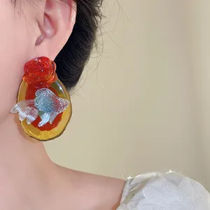 Detailed shot of resin koi goldfish and red rose earrings in new Chinese style
