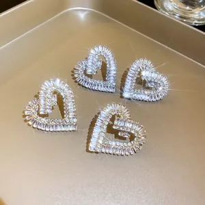 Primo piano di orecchini a lobo a cuore scintillanti con zirconi e logo G su vassoio oro