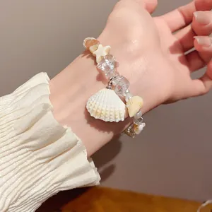 Detailed view of a natural stone pearl bracelet with seashell and starfish charms on a wrist.