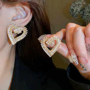 Dettaglio ravvicinato di orecchini a forma di cuore con zirconi e cristalli d'oro